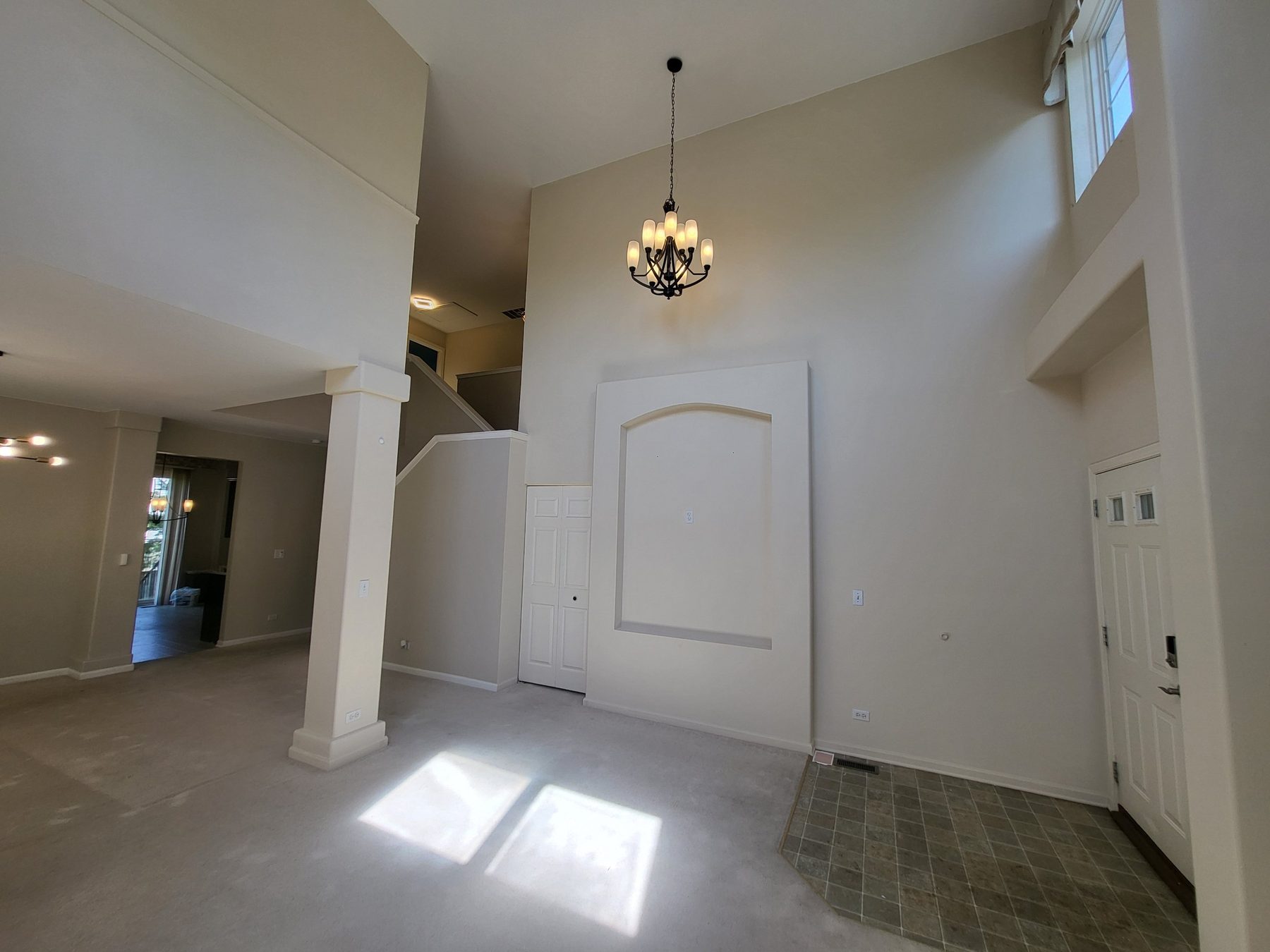 Two-story entry foyer with chandelier, column and arched wall niche, opening into the living room.