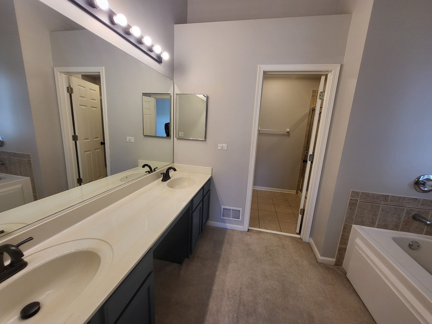 Primary bath with double vanity, full-width mirror, soaking tub under the window and a separate shower.
