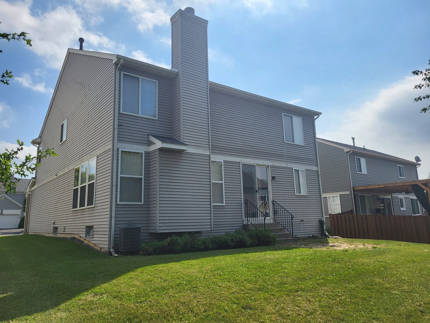 Rear exterior showing the chimney, rear entry with steps and the back lawn.